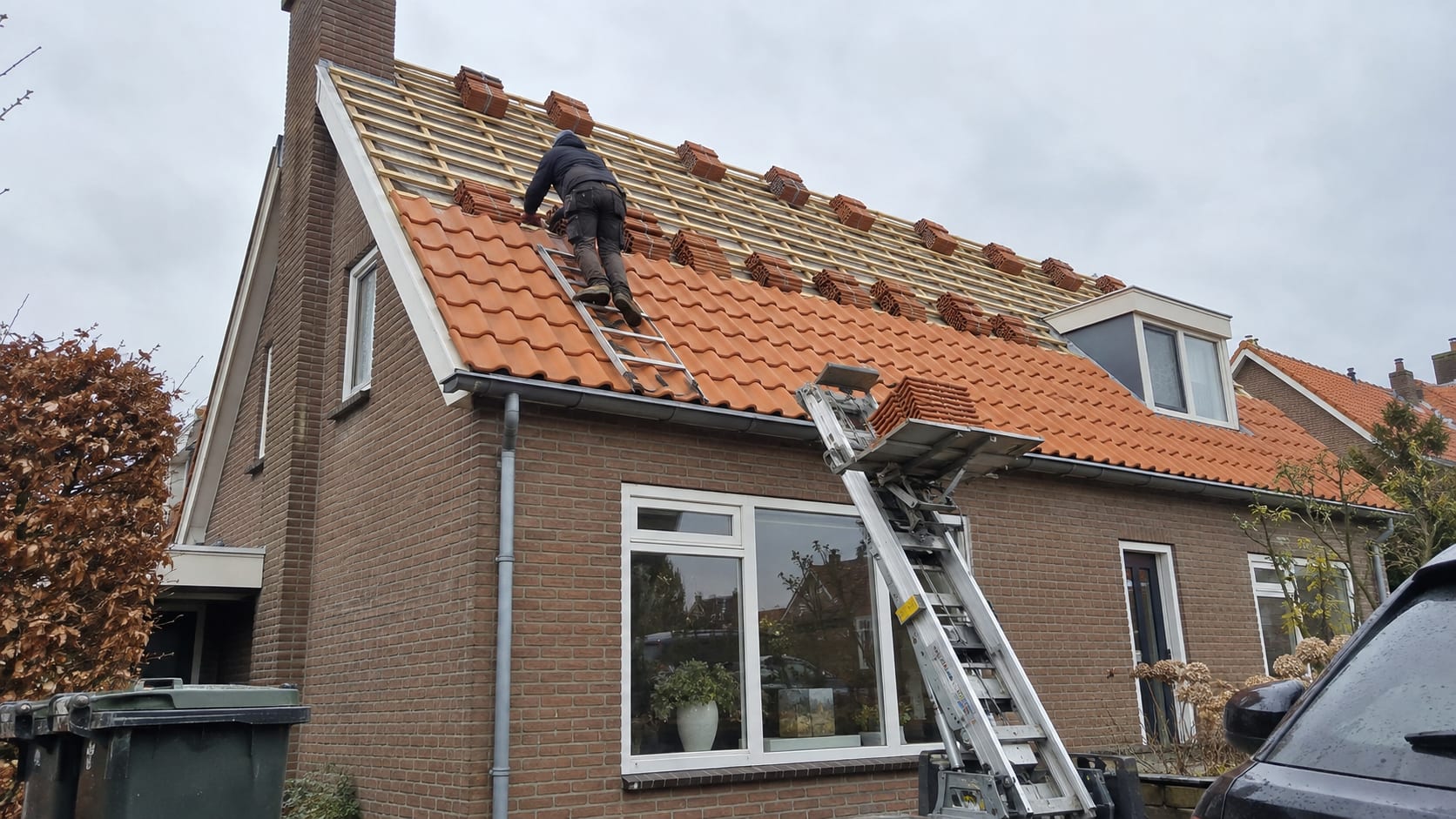 Dakdekker legt nieuwe pannen op een hellend dak met verse panlatten